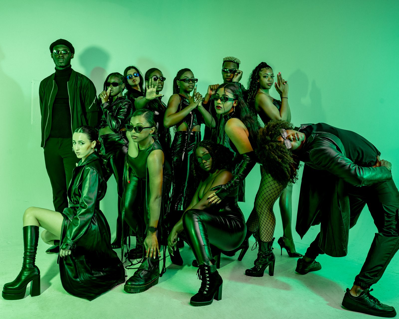 Zayviana in a styled group fashion shoot, everyone in black against a green backdrop